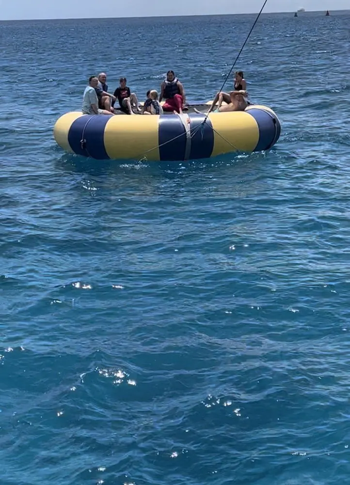 Group of guests sitting on the yellow and blue ocean trampoline floating off Waikiki
